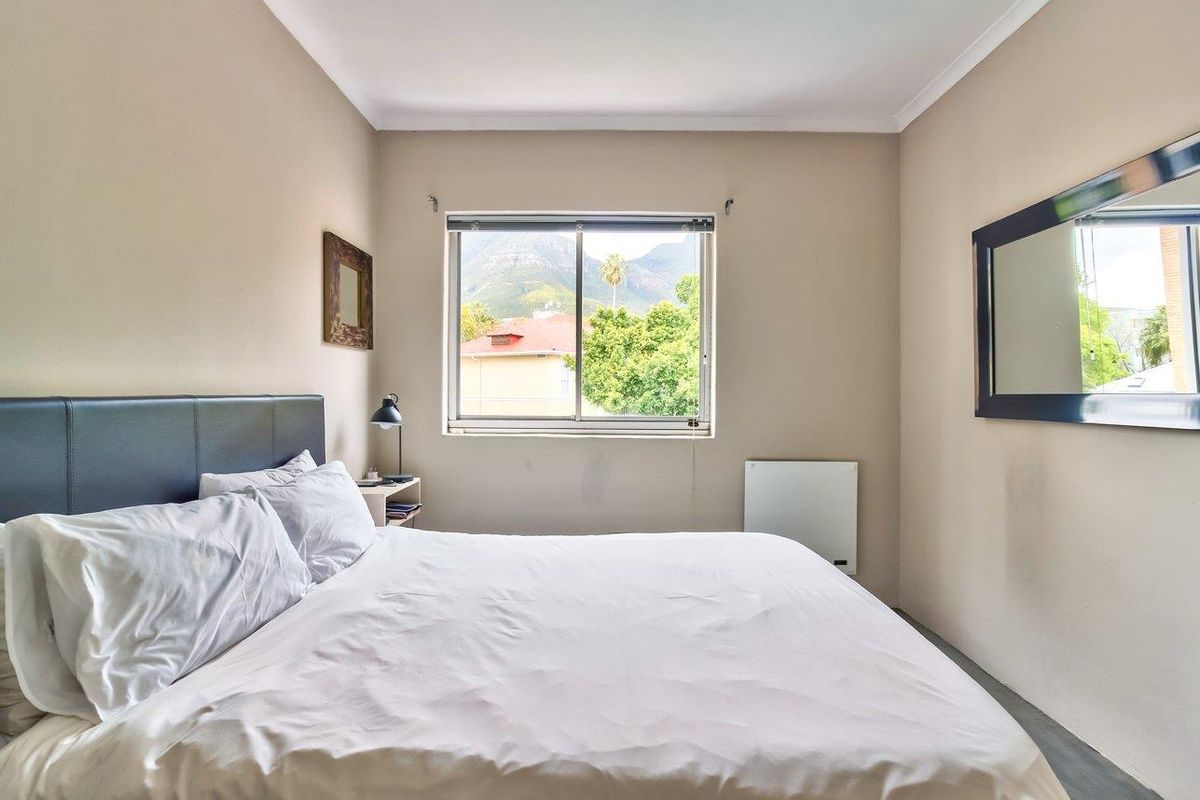 A well-lit bedroom featuring a sliding window with mountain views, neutral wall finishes, and a wall-mounted heater.