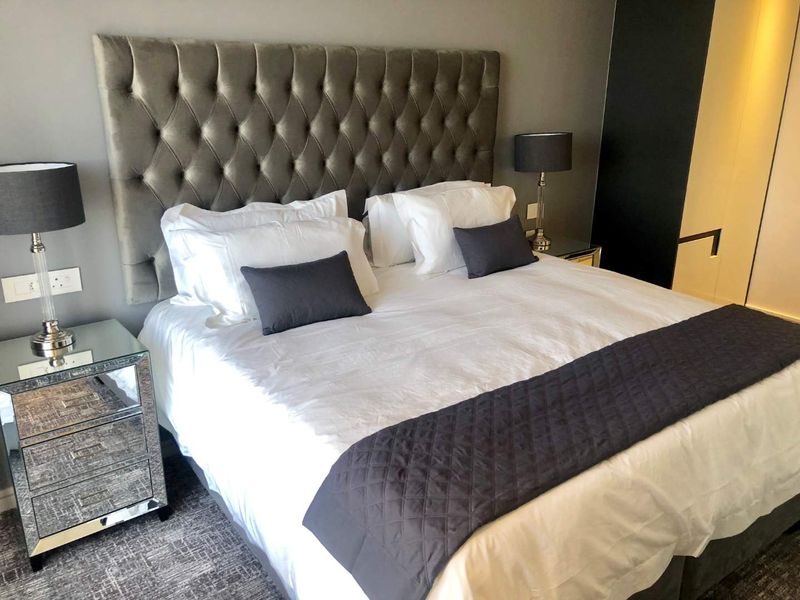 A well-appointed bedroom featuring a large tufted headboard and modern finishes, creating a comfortable and stylish sleeping space.