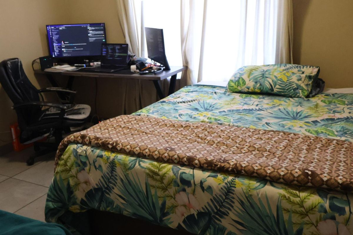 A functional bedroom featuring tiled flooring and natural light from the window, suitable for use as a sleeping area or home office space.