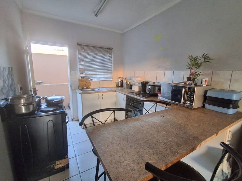 A functional kitchen featuring tiled flooring, laminate countertops, and built-in cabinetry with direct access to an outdoor area.