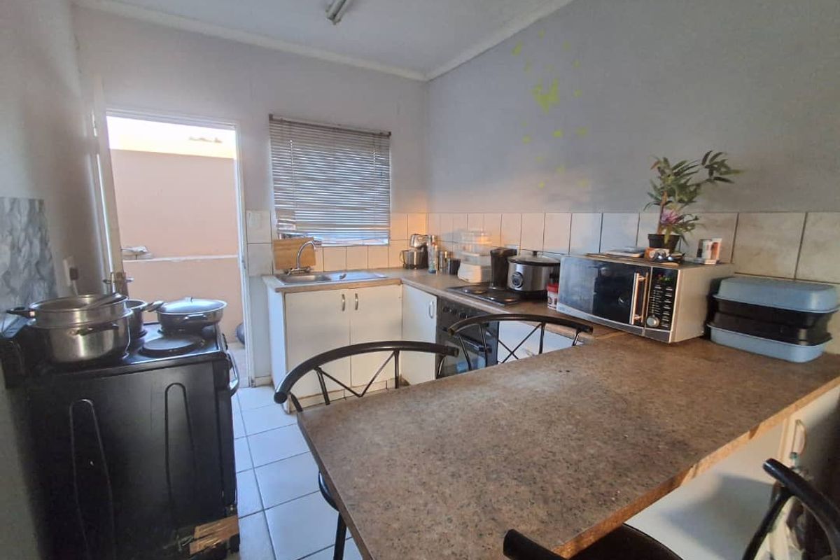 A functional kitchen featuring tiled flooring, laminate countertops, and built-in cabinetry with direct access to an outdoor area.