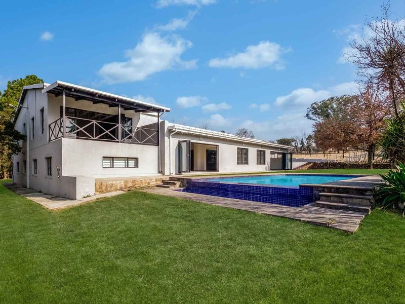 Rear view of the property featuring a swimming pool with tiled surround, a covered patio area, and an elevated balcony with timber balustrades.
