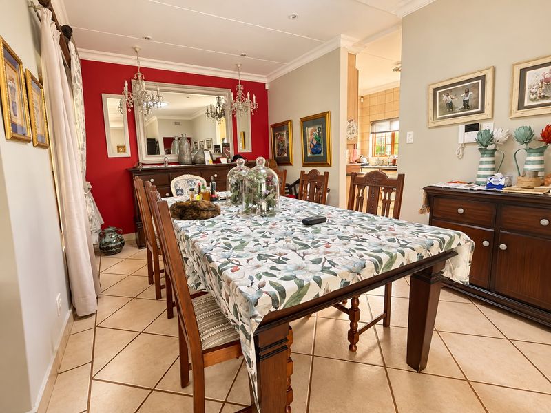 A well-maintained dining room featuring tiled flooring, coved cornicing, and recessed lighting, with an open transition leading into the adjacent kitchen area.