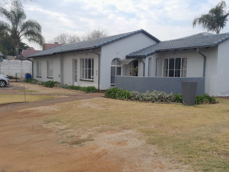 Front view of a single-story residential house featuring a tiled roof, security bars on windows, and a paved walkway leading to the entrance.