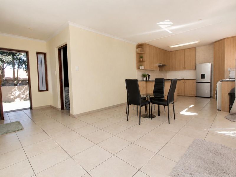 Open-plan living and kitchen area featuring light-toned cabinetry, tiled flooring, and direct access to an outdoor space.