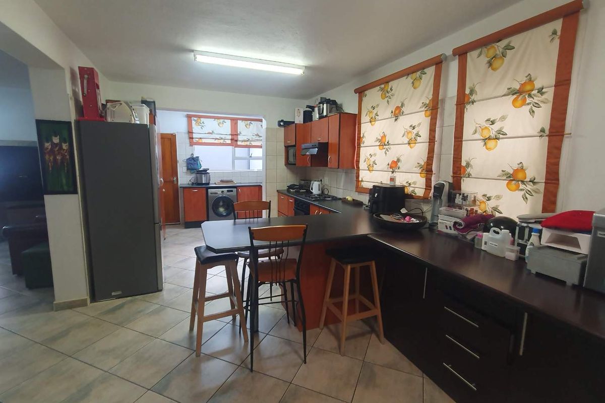 A functional kitchen featuring dark cabinetry, a breakfast bar, and tiled flooring, with an adjacent laundry area visible in the background.