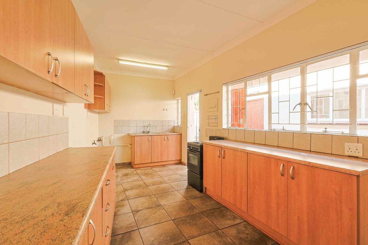 A functional kitchen featuring laminate cabinetry, tiled backsplash, ceramic flooring, and a freestanding stove, offering a clean and practical workspace.