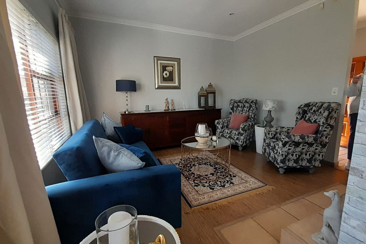 A comfortable living room featuring laminate flooring, a decorative faux brick accent wall, and coved ceiling details, providing a warm and inviting atmosphere.