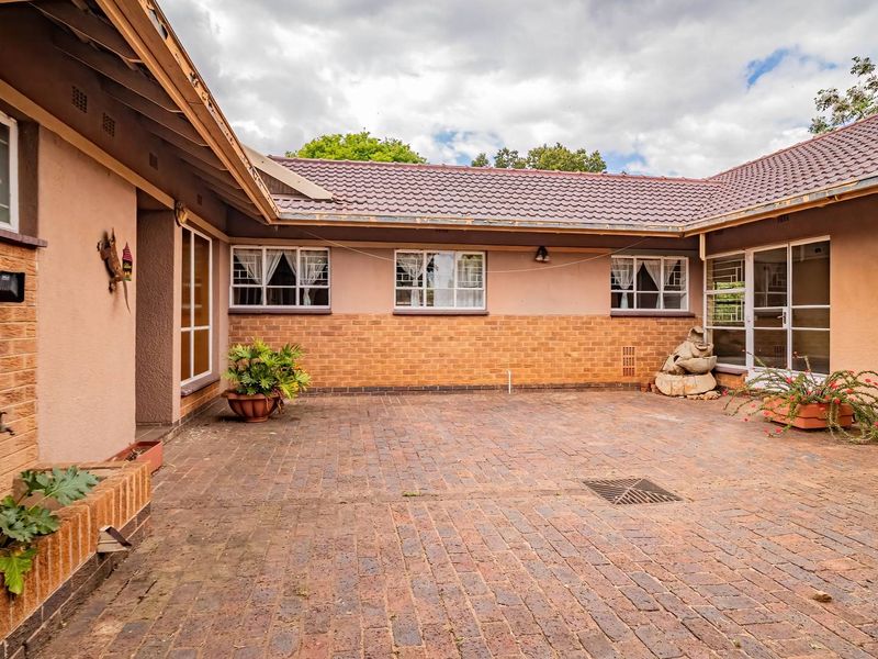 A spacious rear courtyard featuring brick paving, tiled roofing, and direct access to the home's exterior living areas.