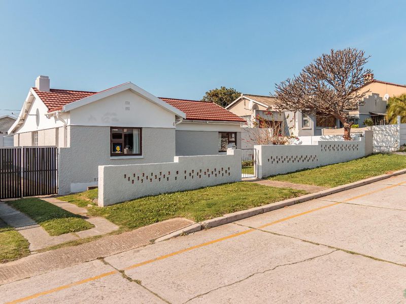 Front elevation of a single-story house featuring a tiled roof, decorative boundary wall, and gated entrance.