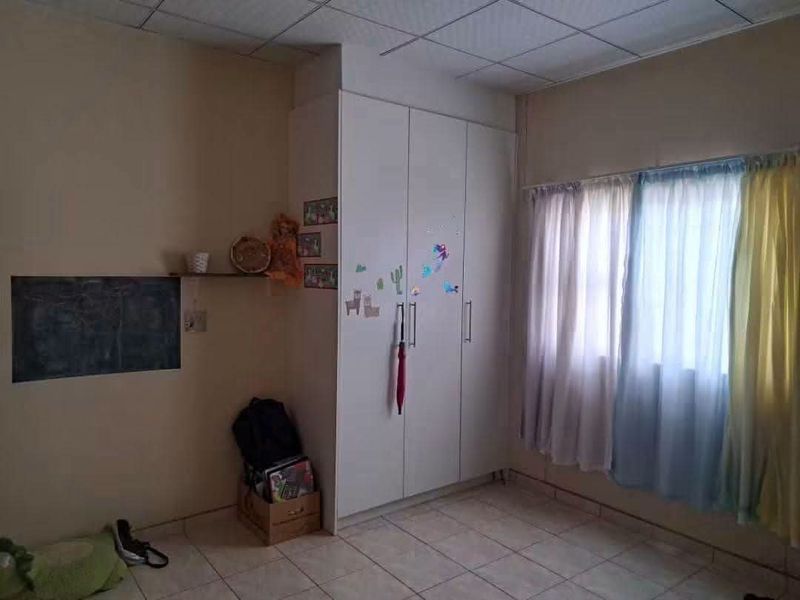 A bedroom featuring tiled flooring, a built-in wardrobe, and a drop ceiling, offering a functional space ready for cosmetic updates.