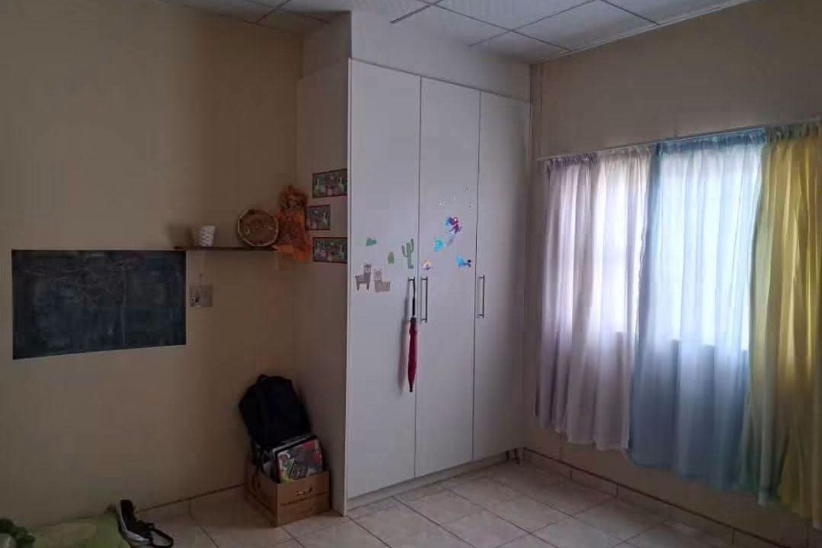 A bedroom featuring tiled flooring, a built-in wardrobe, and a drop ceiling, offering a functional space ready for cosmetic updates.