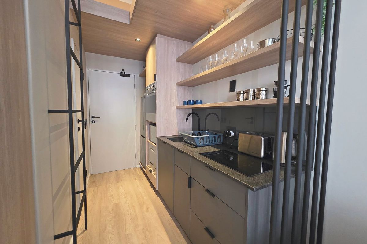 Modern compact kitchen featuring sleek dark cabinetry, stone countertops, integrated appliances, and stylish open shelving with recessed ceiling lighting.