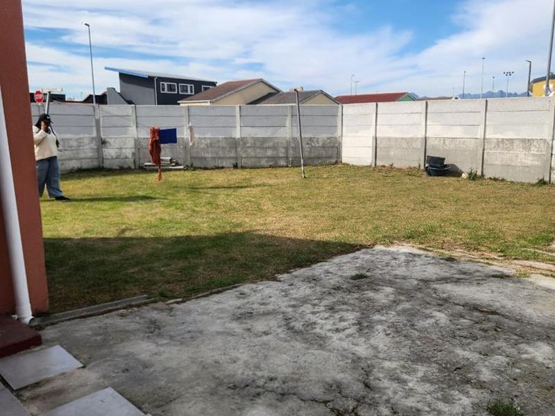 A private rear garden featuring a concrete patio area and a fully enclosed precast concrete boundary wall.