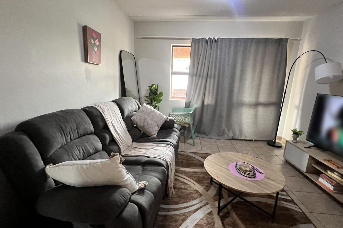 A comfortable living room featuring tiled flooring and a window, providing a functional and inviting space for relaxation.