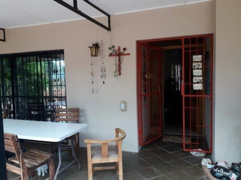 A covered patio area featuring tiled flooring and security gates, providing a functional outdoor space for relaxation or entertainment.