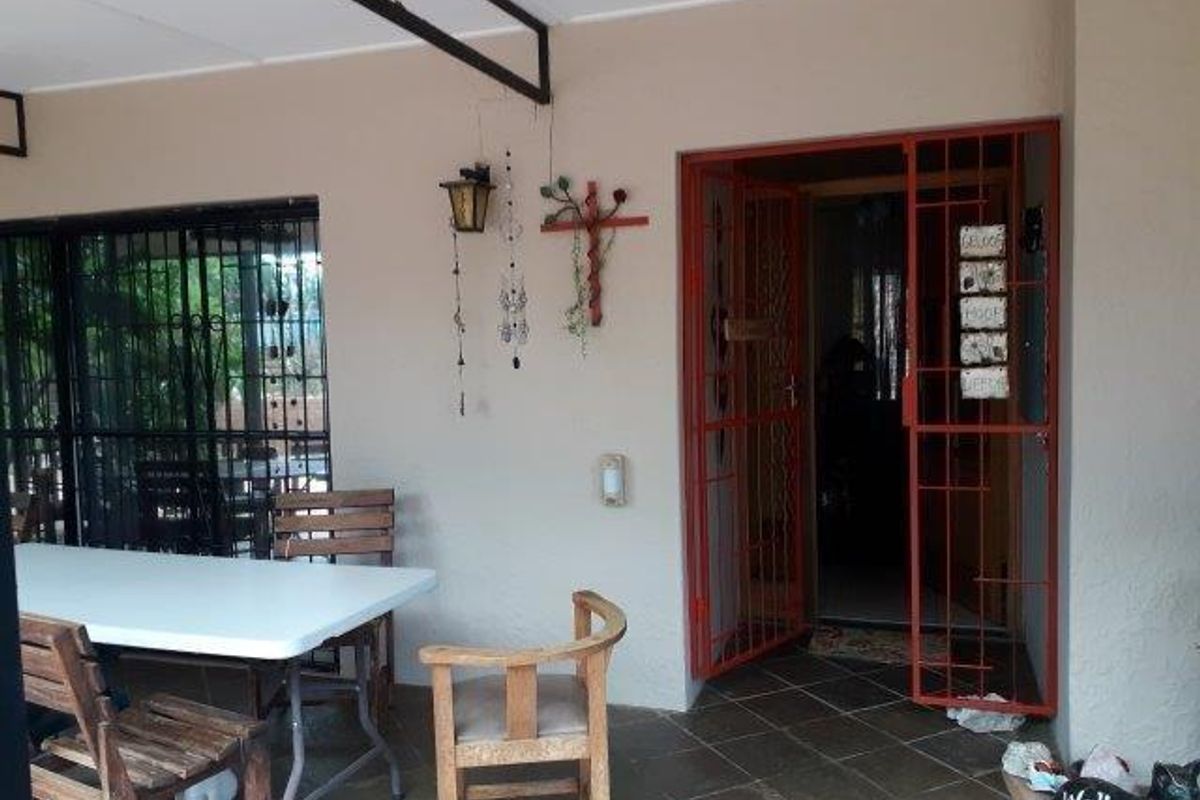 A covered patio area featuring tiled flooring and security gates, providing a functional outdoor space for relaxation or entertainment.