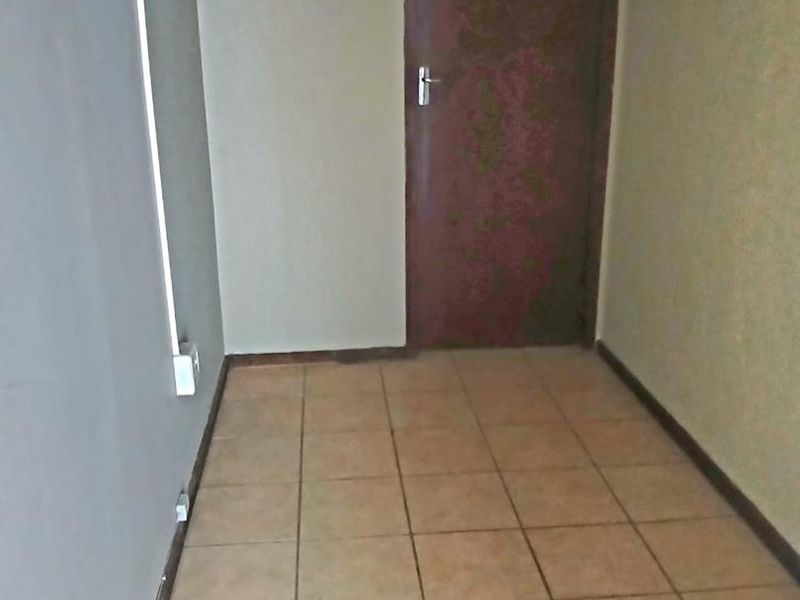 A vacant office space featuring tiled flooring and a single internal door, requiring cosmetic updates to improve its professional appeal.