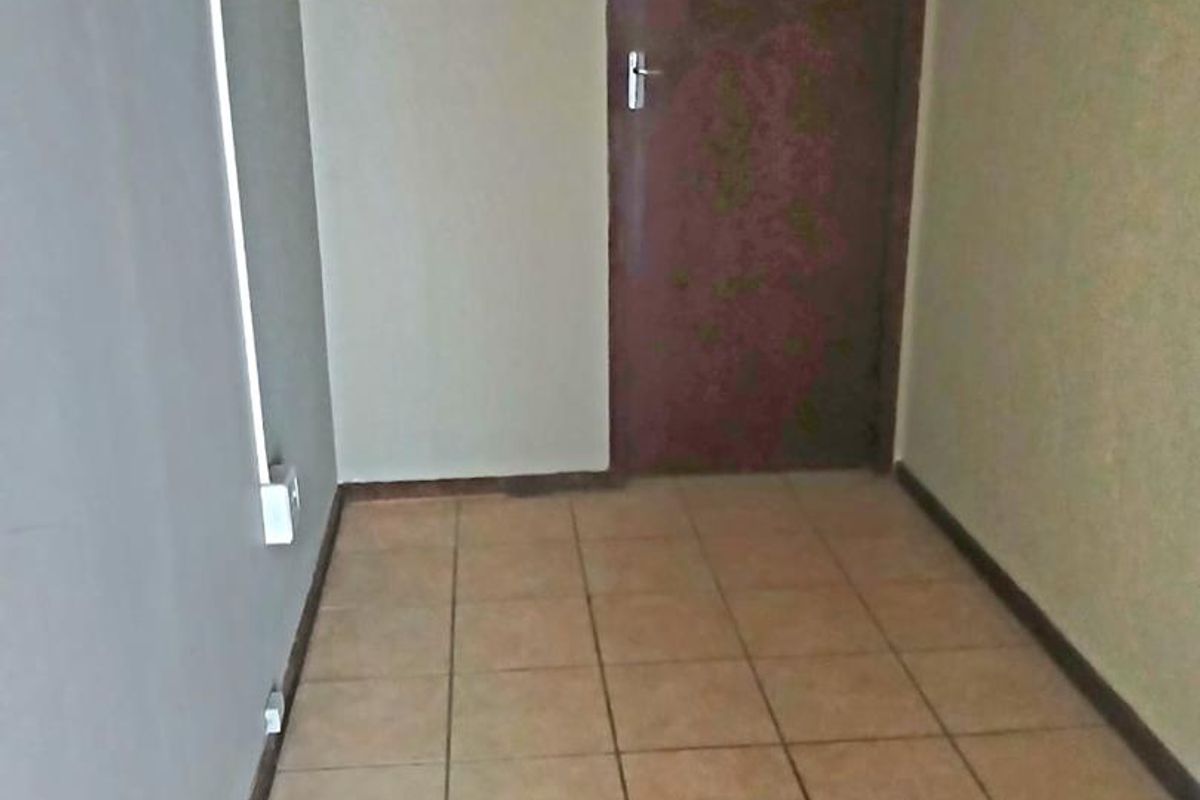 A vacant office space featuring tiled flooring and a single internal door, requiring cosmetic updates to improve its professional appeal.