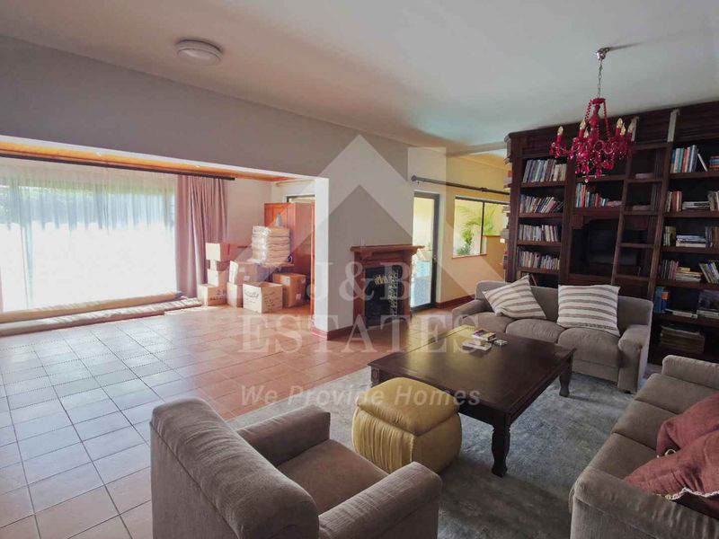Spacious open-plan living area featuring a large built-in bookshelf, a central fireplace, and tiled flooring with direct access to the outdoor area.