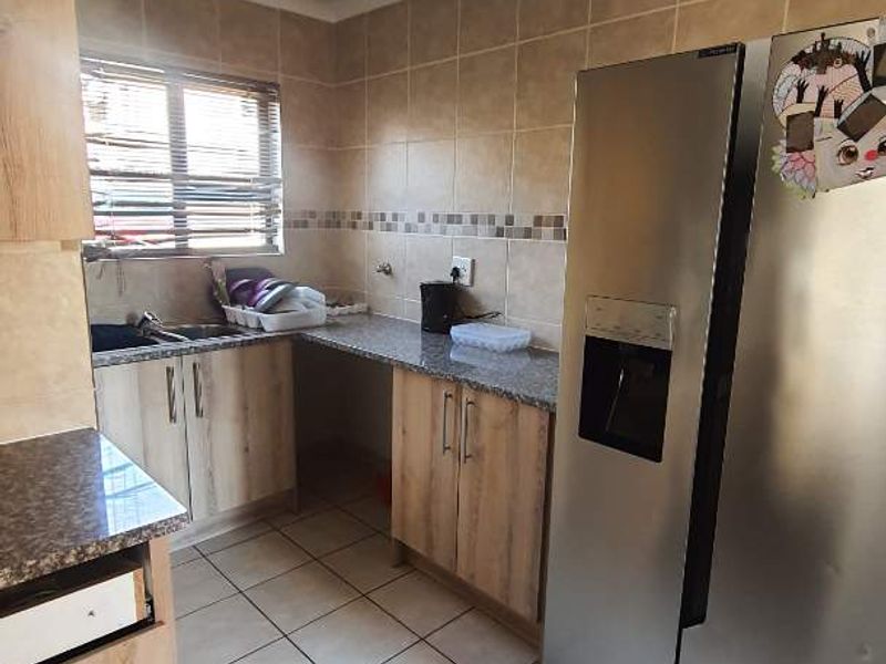 Functional kitchen featuring light wood-finish cabinetry, granite countertops, tiled backsplash, and tiled flooring. Includes a dedicated space for a large refrigerator.