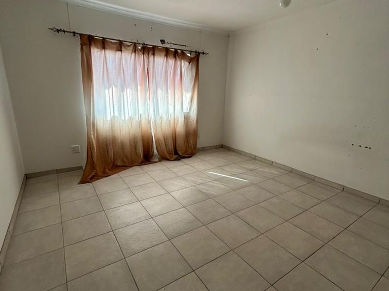 An empty bedroom featuring tiled flooring and neutral walls, ready for personalization and staging.