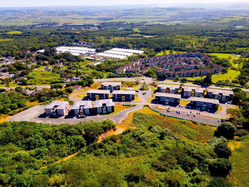 Aerial view of a modern apartment complex development surrounded by lush green landscape and natural vegetation.