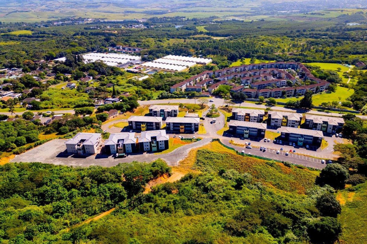 Aerial view of a modern apartment complex development surrounded by lush green landscape and natural vegetation.