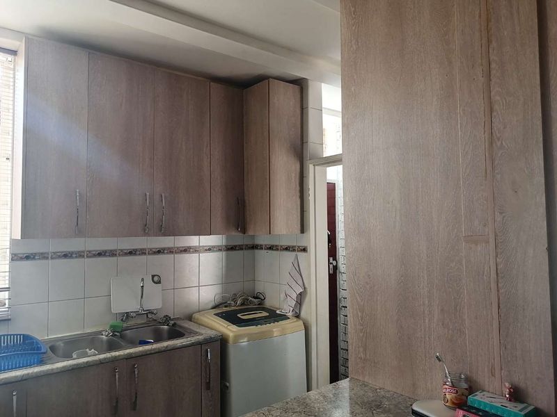 A functional kitchen area featuring wood-look laminate cabinetry, a double bowl stainless steel sink, and a tiled backsplash.