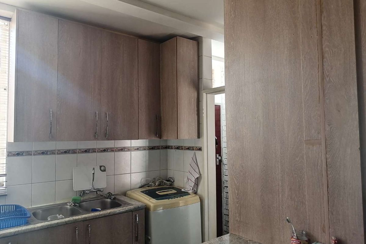 A functional kitchen area featuring wood-look laminate cabinetry, a double bowl stainless steel sink, and a tiled backsplash.