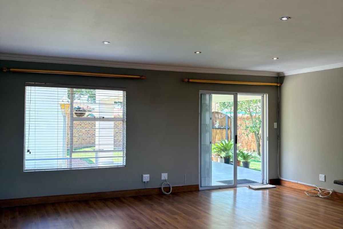 Spacious living area featuring warm-toned laminate flooring, recessed ceiling lighting, and sliding glass doors providing direct access to the outdoor patio.