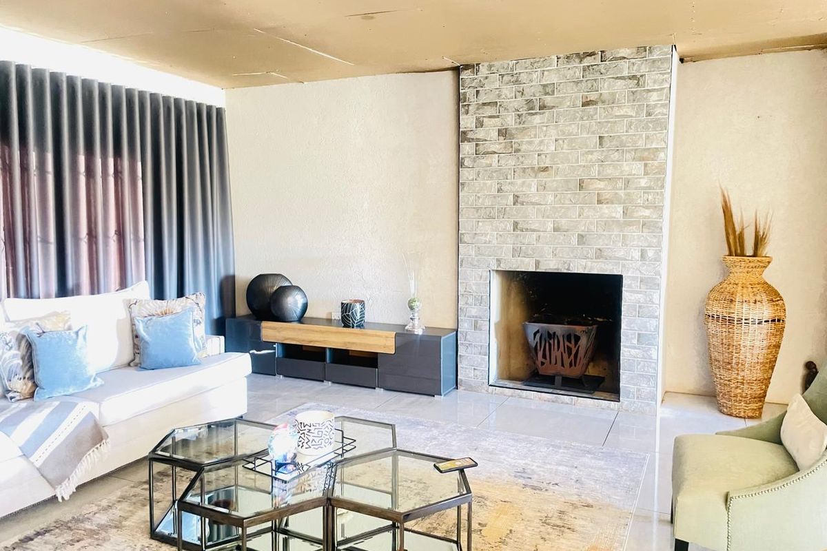 Living room featuring a prominent brick fireplace and tiled flooring, currently requiring ceiling completion and cosmetic updates.