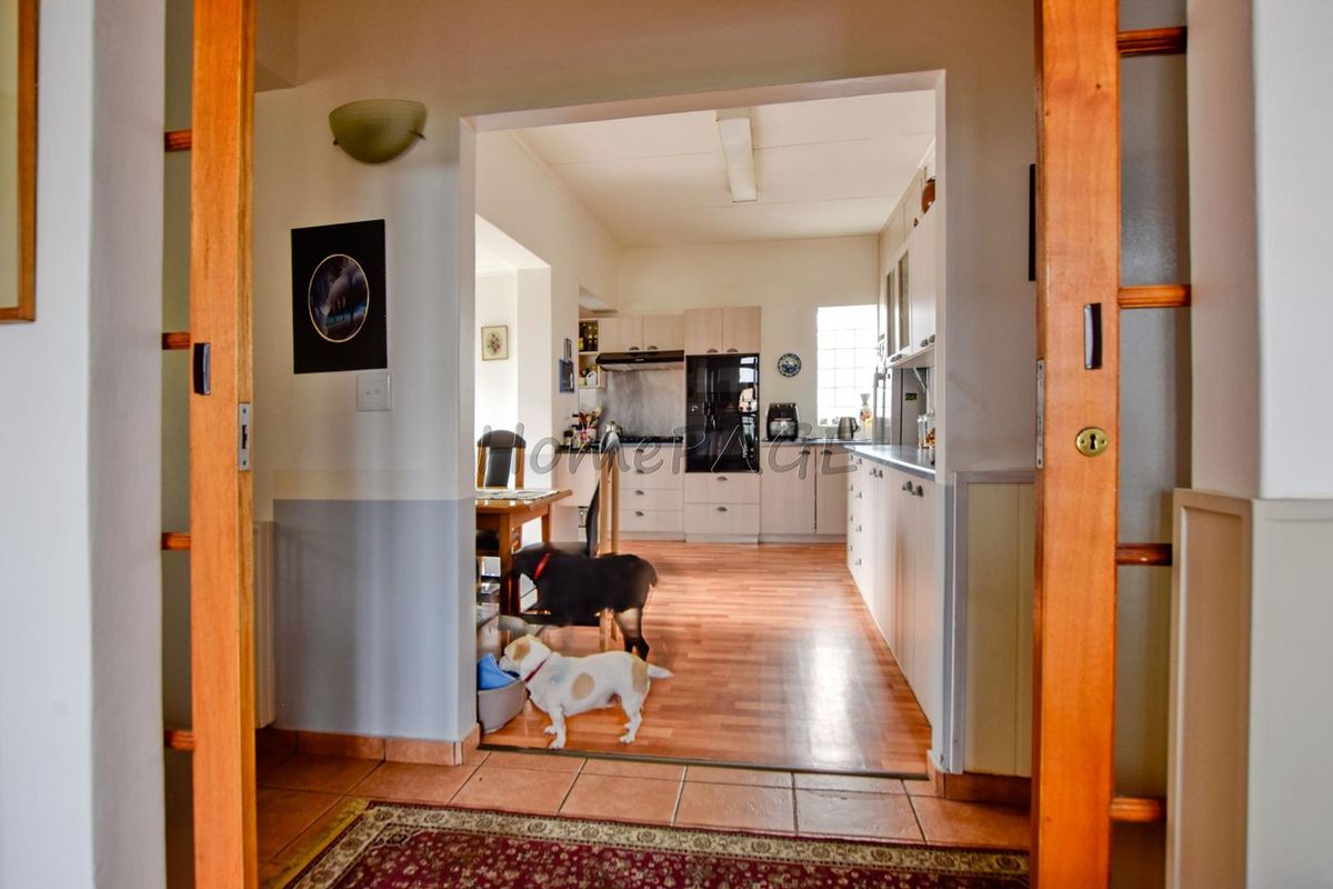 A view from the hallway into a functional kitchen featuring built-in cabinetry, integrated appliances, and wood-look flooring.
