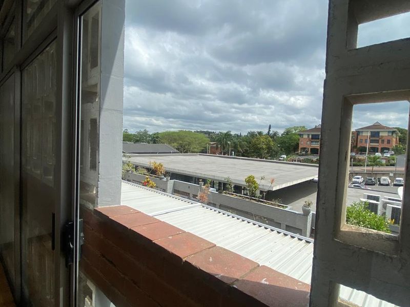 A balcony area featuring a brick parapet wall and decorative breeze block screen, offering an elevated view of the surrounding complex and parking area.
