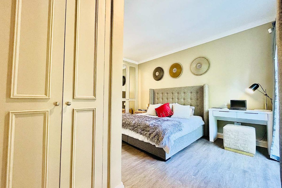 A well-maintained bedroom featuring built-in cupboards, light wood-look flooring, and neutral wall finishes, offering a comfortable and functional living space.