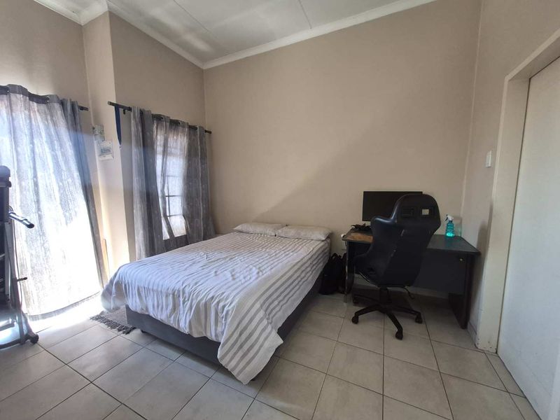 A bedroom featuring tiled flooring and a sliding glass door providing natural light.