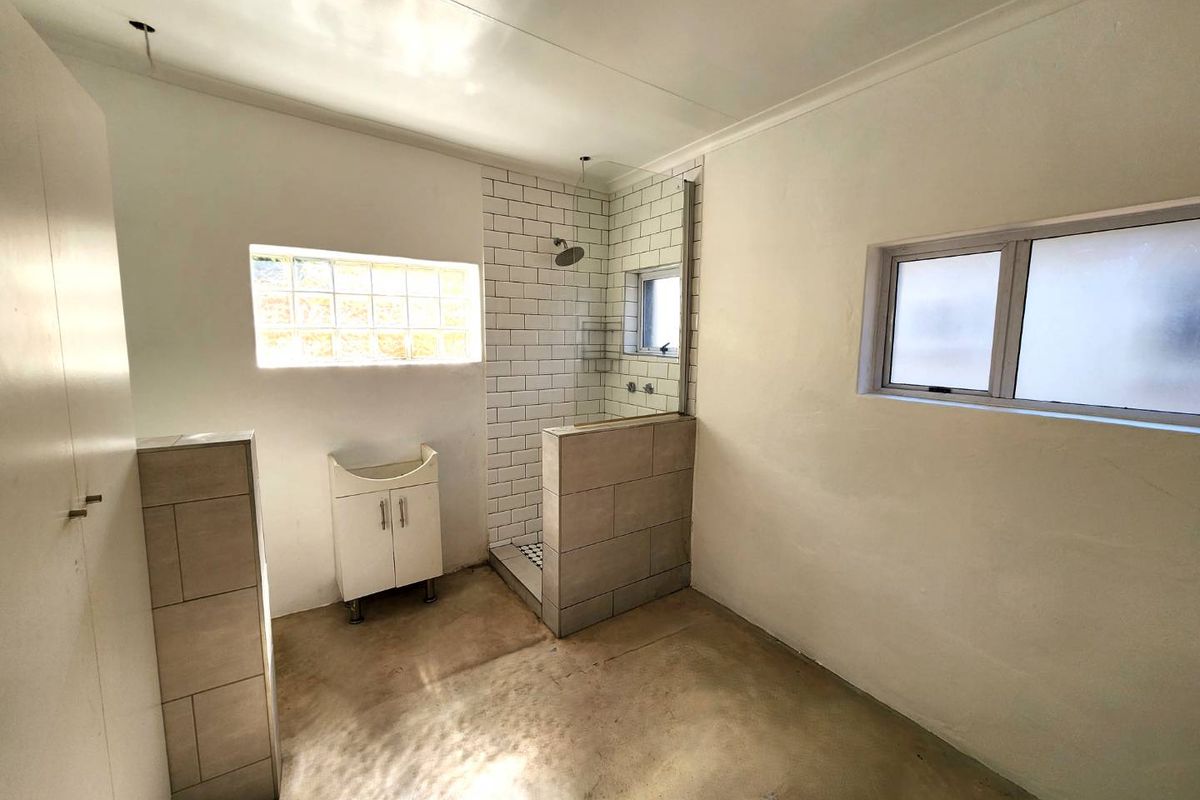 A functional bathroom featuring a walk-in shower with subway tile surround, glass block window, and a compact vanity unit.