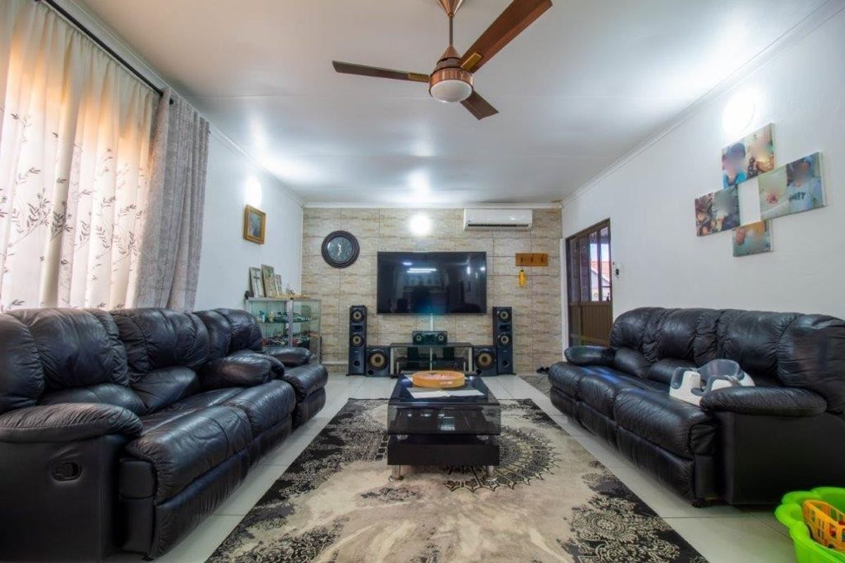 A comfortable living room featuring tiled flooring, a ceiling fan, a split-system air conditioner, and a decorative feature wall.