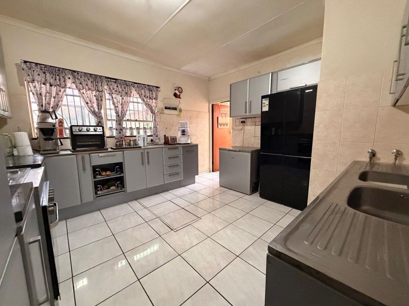 A functional kitchen featuring grey built-in cabinetry, tiled flooring, and a double basin sink with ample counter space.
