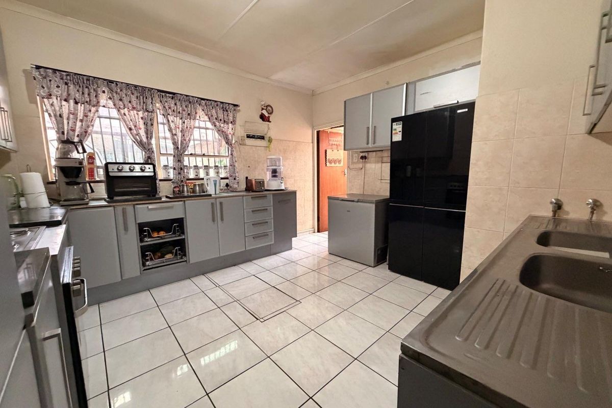 A functional kitchen featuring grey built-in cabinetry, tiled flooring, and a double basin sink with ample counter space.