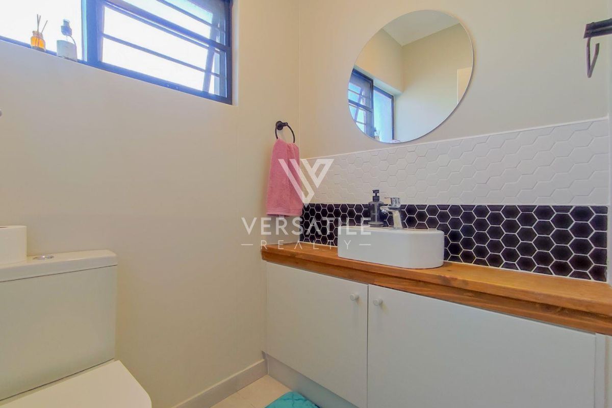 Modern bathroom featuring a timber-topped vanity with a vessel sink, stylish hexagonal tile backsplash, and a functional toilet.