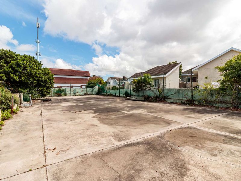 A large, paved vacant residential lot featuring concrete surfacing and perimeter chain link fencing, suitable for development or outdoor use.