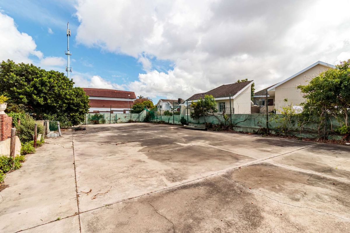A large, paved vacant residential lot featuring concrete surfacing and perimeter chain link fencing, suitable for development or outdoor use.
