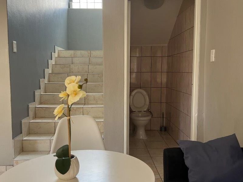 Interior view showing a tiled staircase with a glass block window and an adjacent small bathroom with tiled walls and flooring.