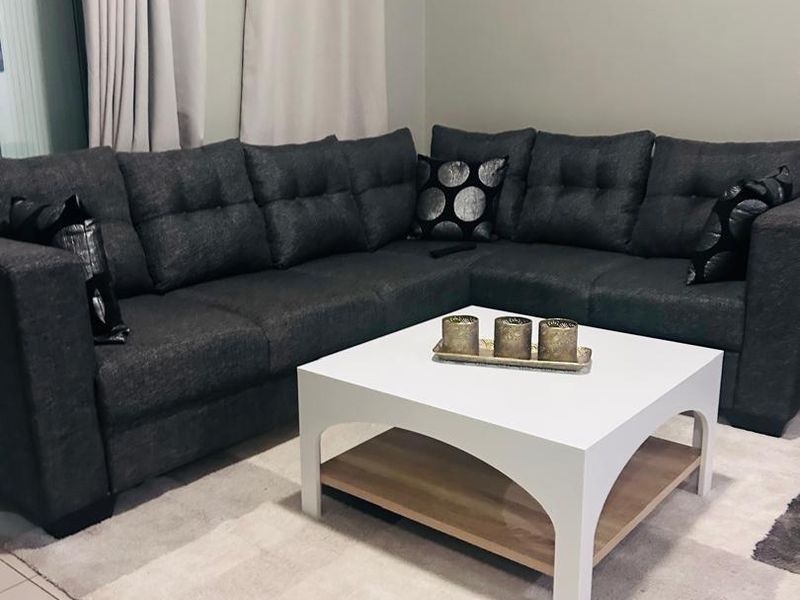 A comfortable living room area featuring neutral tiled flooring and access to an outdoor space via a sliding glass door.