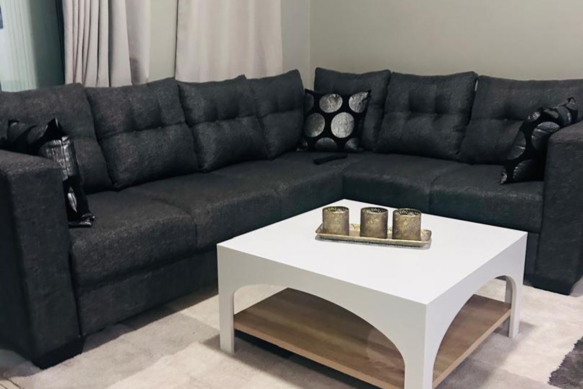 A comfortable living room area featuring neutral tiled flooring and access to an outdoor space via a sliding glass door.