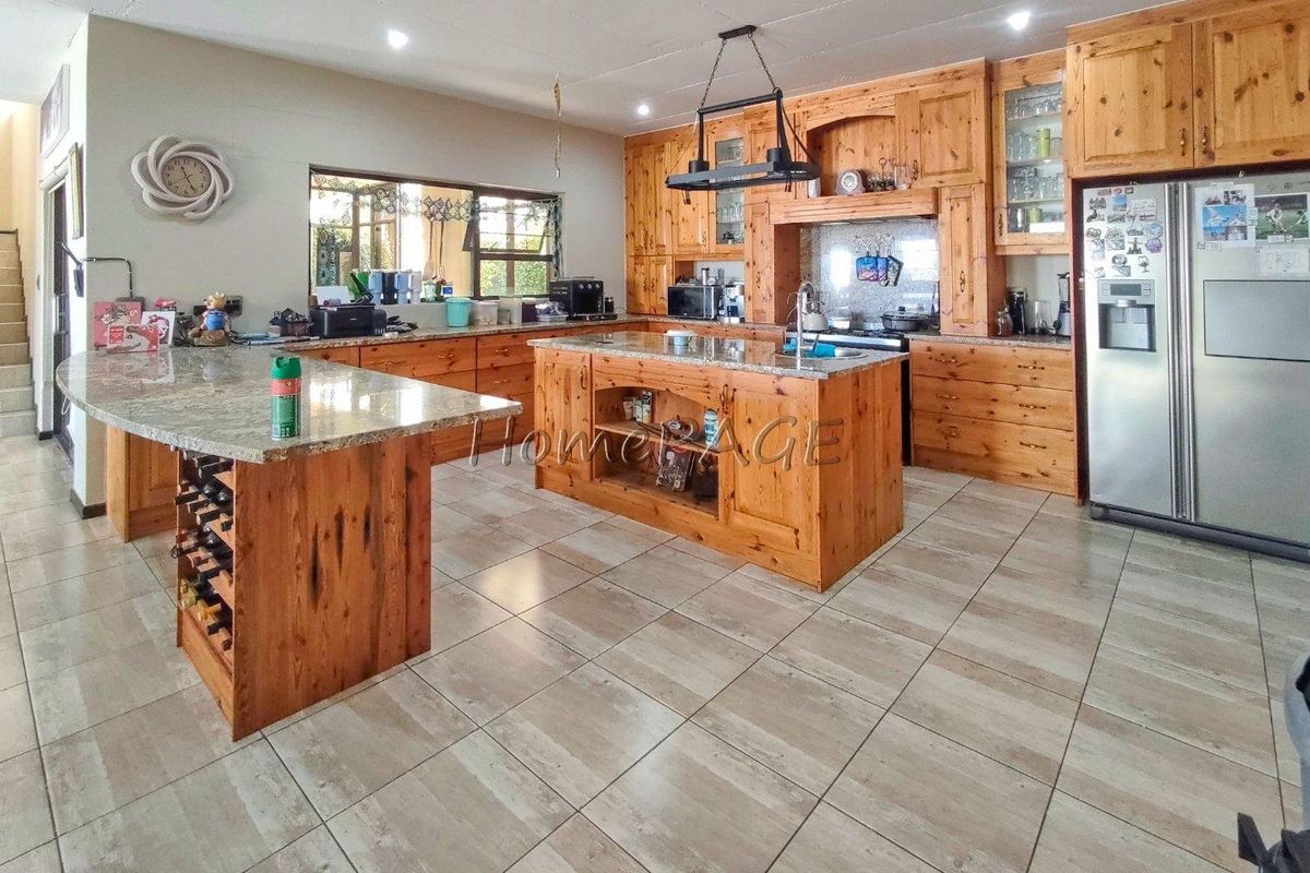 Spacious kitchen featuring extensive knotty pine cabinetry, granite countertops, a central island with integrated wine storage, and large-format floor tiles.