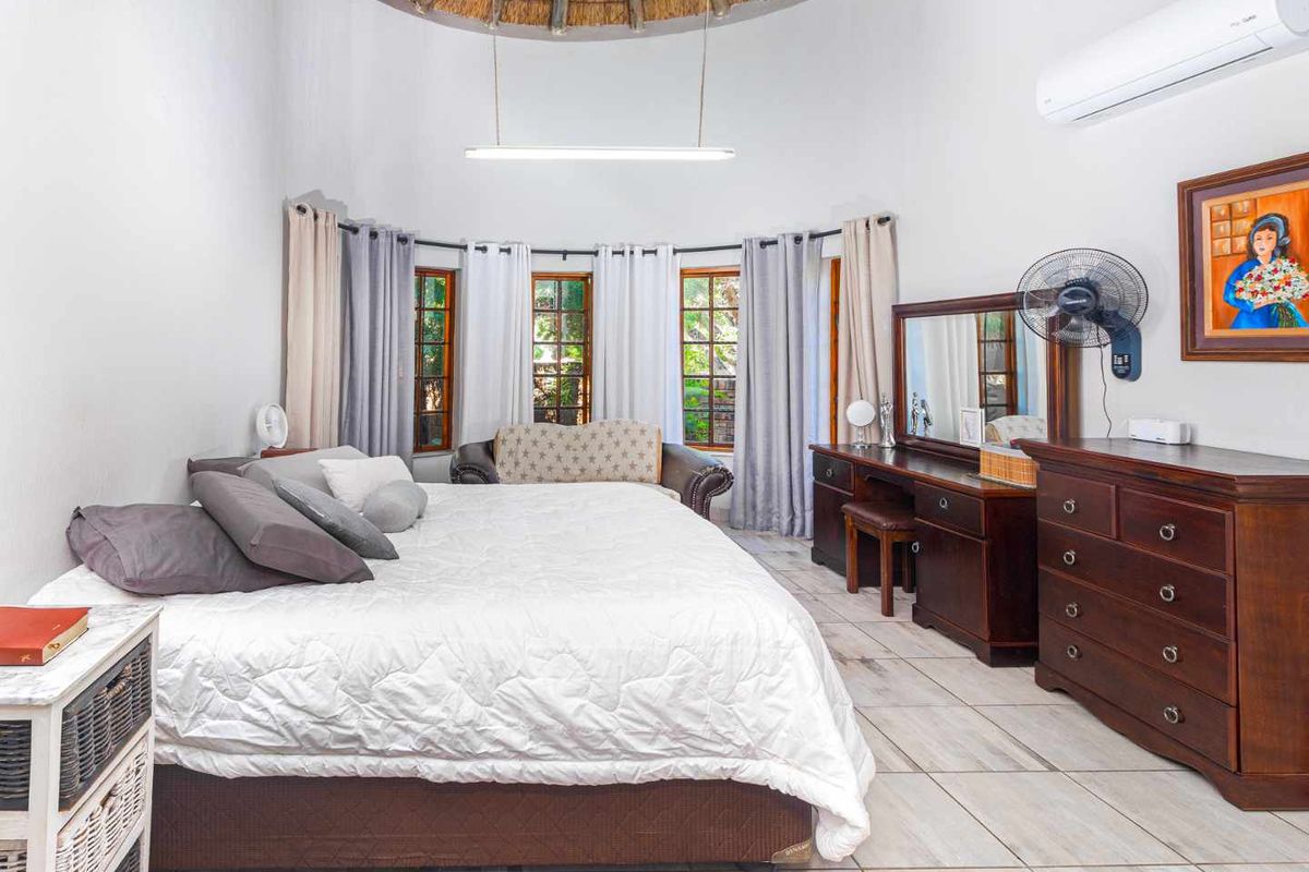 Spacious bedroom featuring a unique vaulted thatched ceiling, tiled flooring, and large windows that provide ample natural light.
