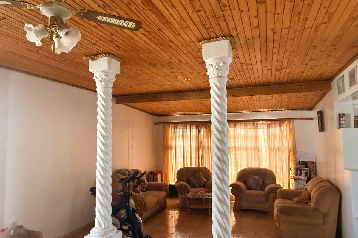 Living room featuring decorative spiral columns, a timber-clad ceiling with a ceiling fan, and tiled flooring with natural light from large windows.