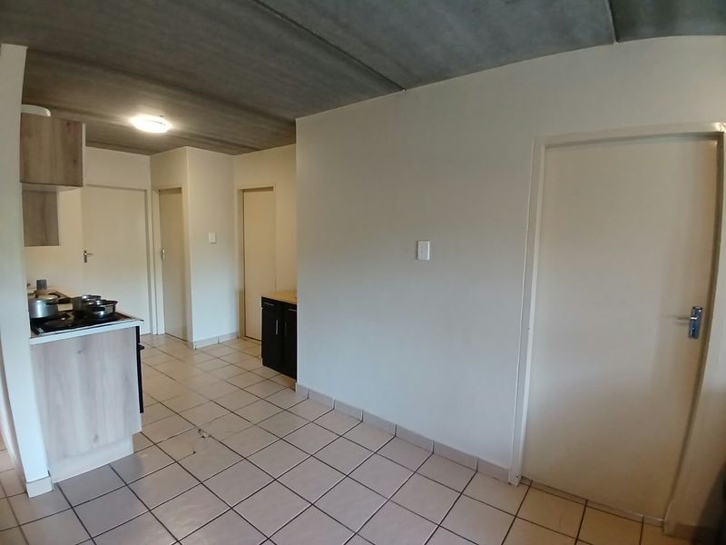 A functional kitchen area featuring built-in cabinetry, tiled flooring, and an exposed concrete ceiling, offering a blank canvas for potential updates.